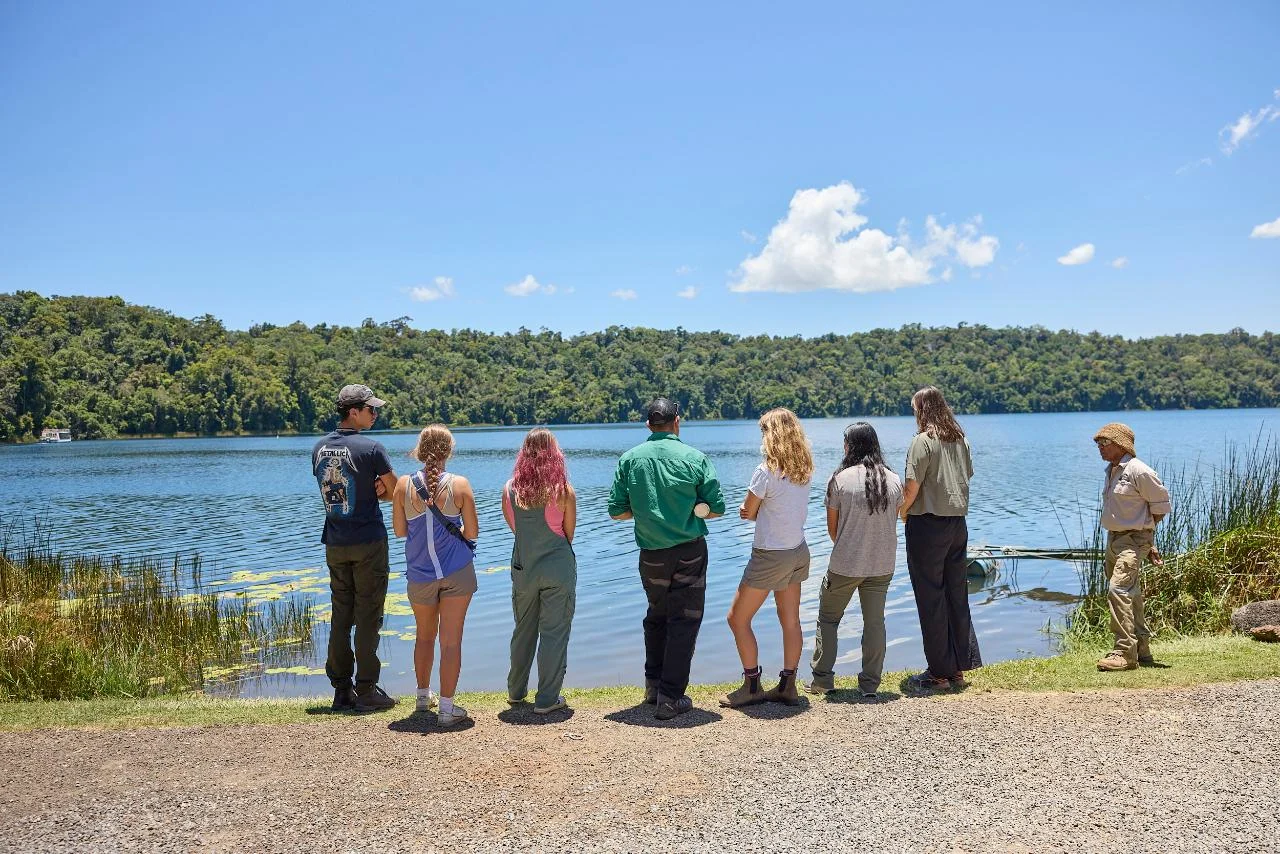 A Yidinji guide and visitors face Lake Barrine from the rainforest edge