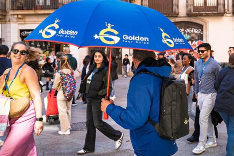 A Golden Tour Guide leader holding the blue umbrella used as the walking tour meeting marker