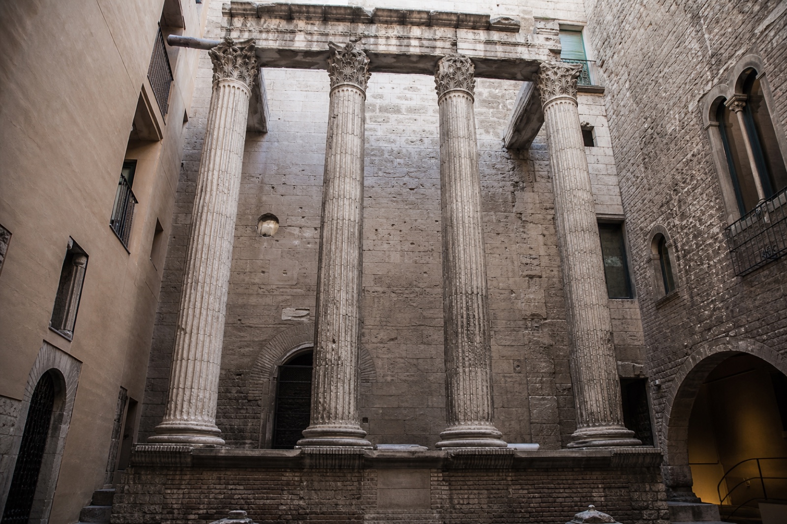 Four surviving Corinthian columns of the Temple of Augustus rise inside later courtyard walls