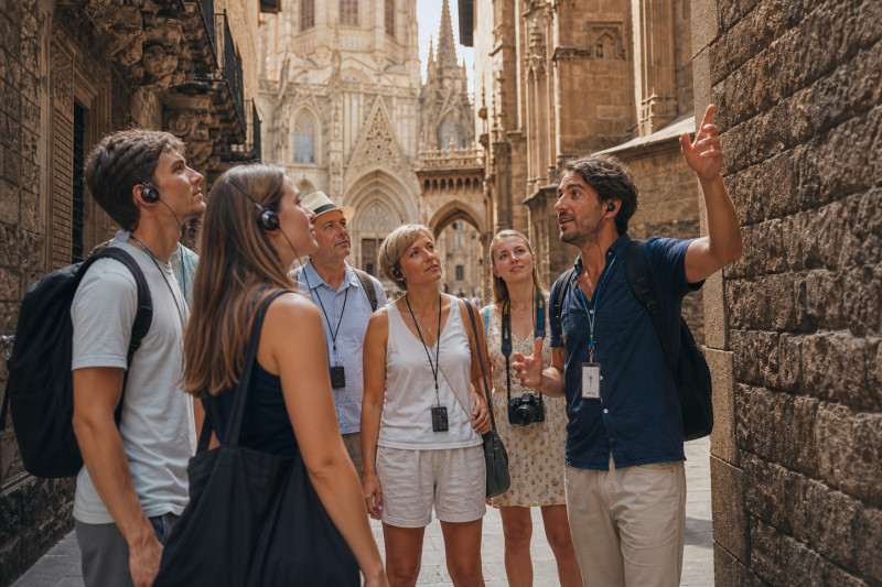 A local guide speaking to travellers in a narrow lane beside Barcelona Cathedral