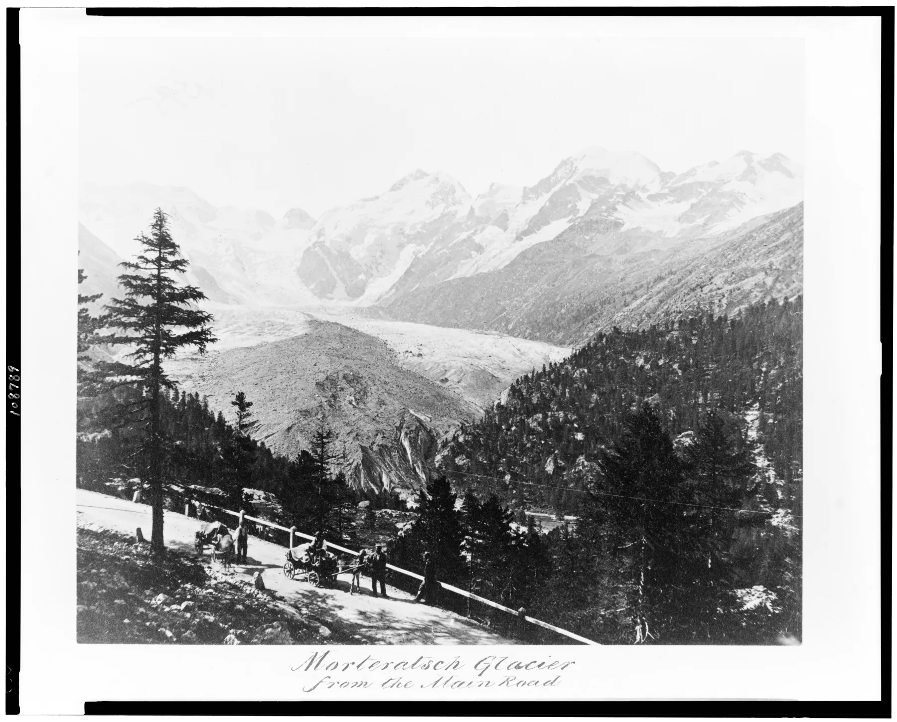 Historic black-and-white view of the Morteratsch Glacier extending far down its valley above a road with people and horse-drawn vehicles.