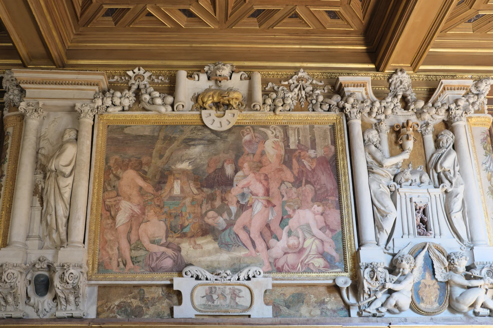 Fresco, stucco, emblems and carved architecture form one dense wall programme in the Galerie François I.