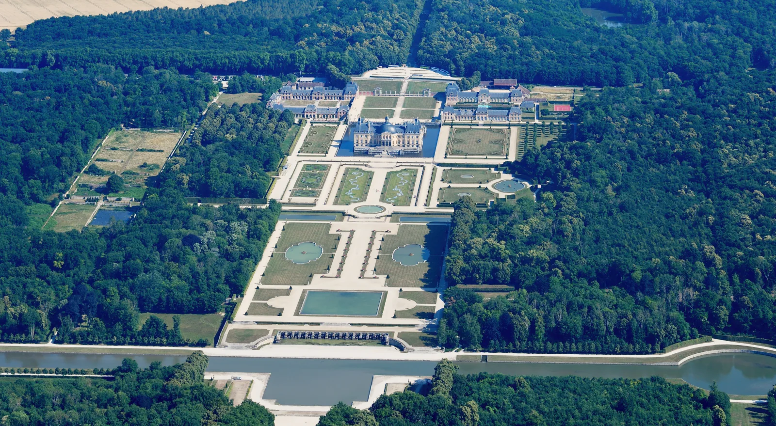 An aerial view shows the château, moat, parterres, basins, canal and woodland aligned at Vaux-le-Vicomte.