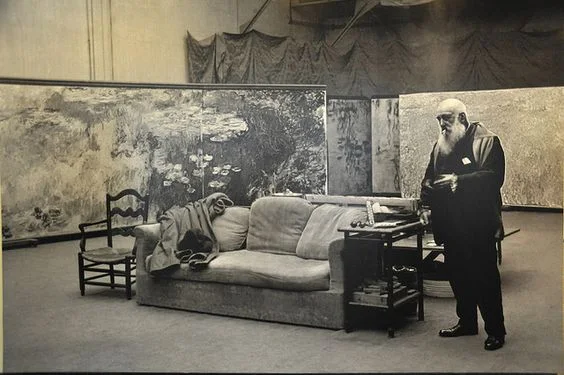 Claude Monet stands beside large Water Lilies canvases in his Giverny studio in 1920.