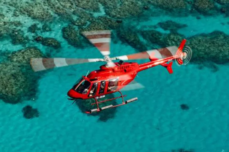 An operator-supplied exact-product image shows a red helicopter above shallow reef water.