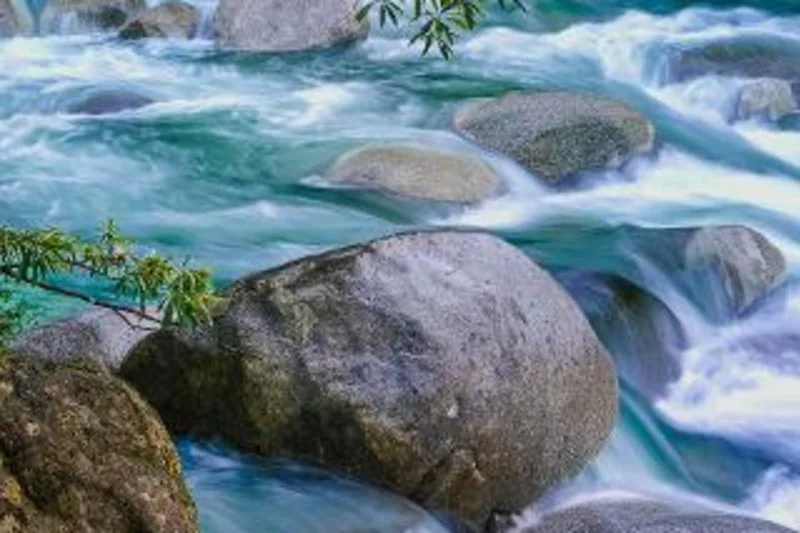 Fast water moves between large granite boulders in Mossman Gorge