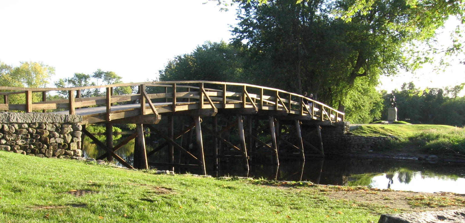 The reconstructed wooden North Bridge over the Concord River, framed by open banks and trees.