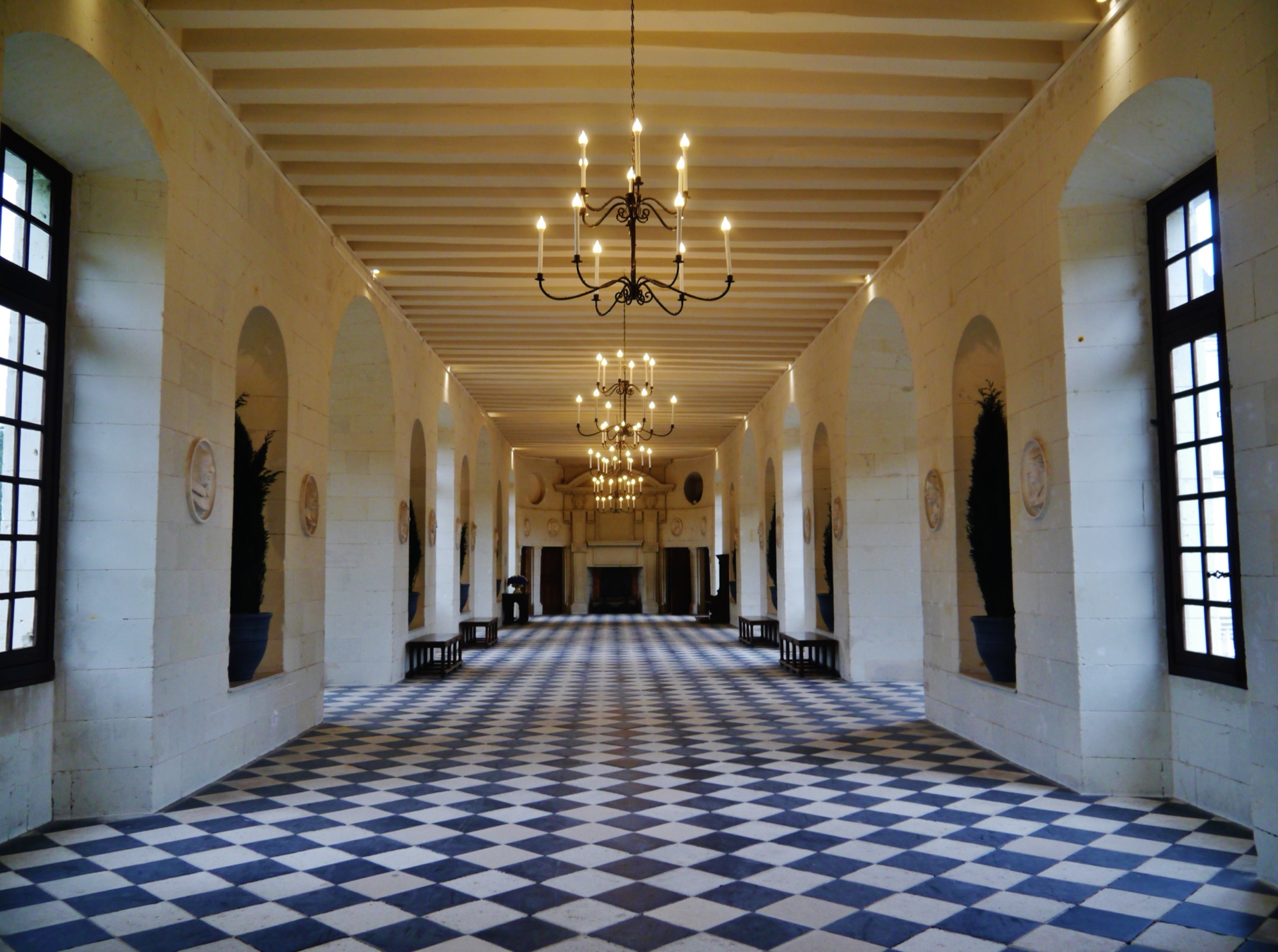 The long gallery at Chenonceau uses repeated windows to keep the river present inside the building.