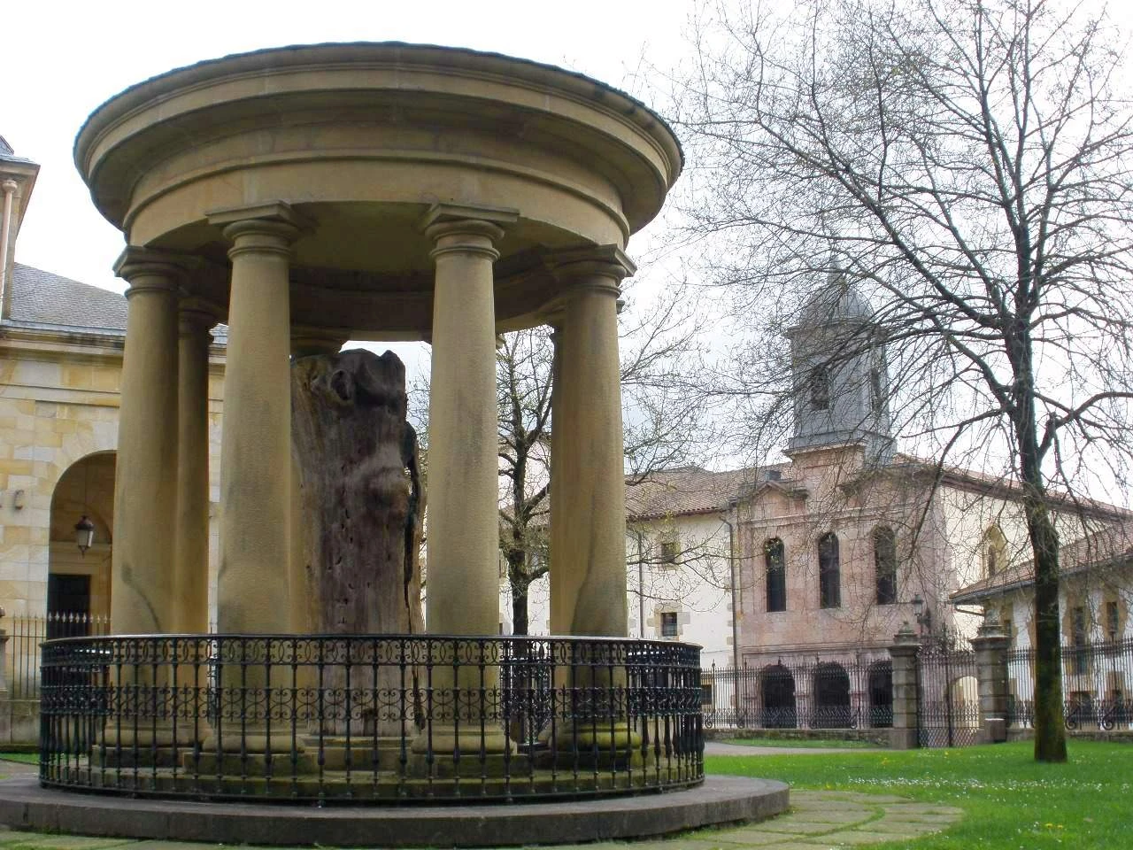 The preserved Old Tree of Gernika stands inside a circular stone colonnade, with the Assembly House behind it.