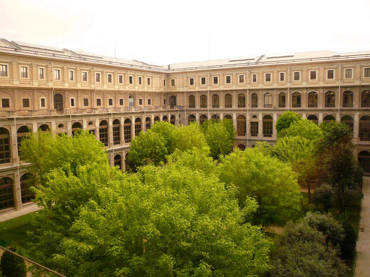 The Sabatini courtyard is enclosed by repeated tiers of arched and rectangular windows above a densely planted garden.
