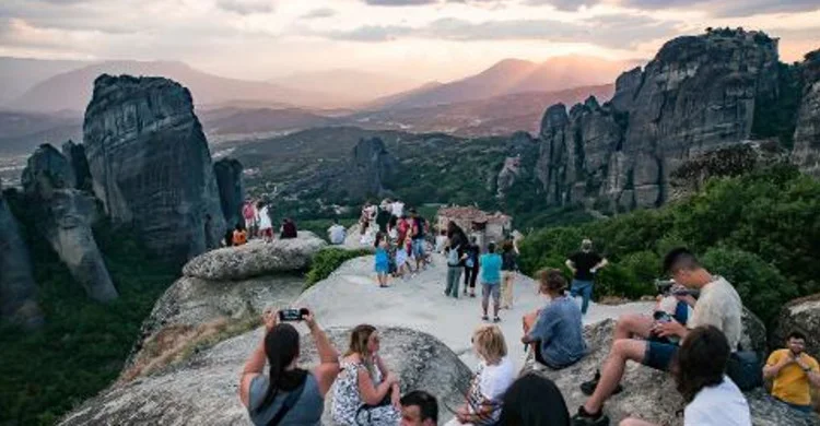 Visitors gather on exposed rock at a popular Meteora sunset viewpoint.