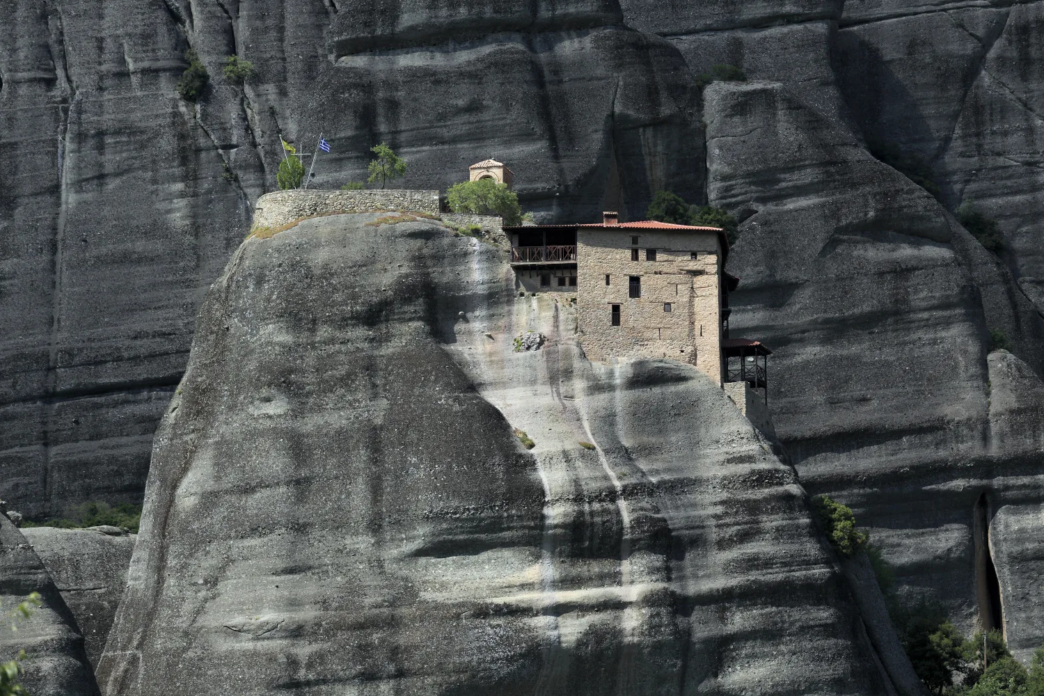 St Nicholas Anapafsas compressed onto a small rock beneath much larger conglomerate walls.