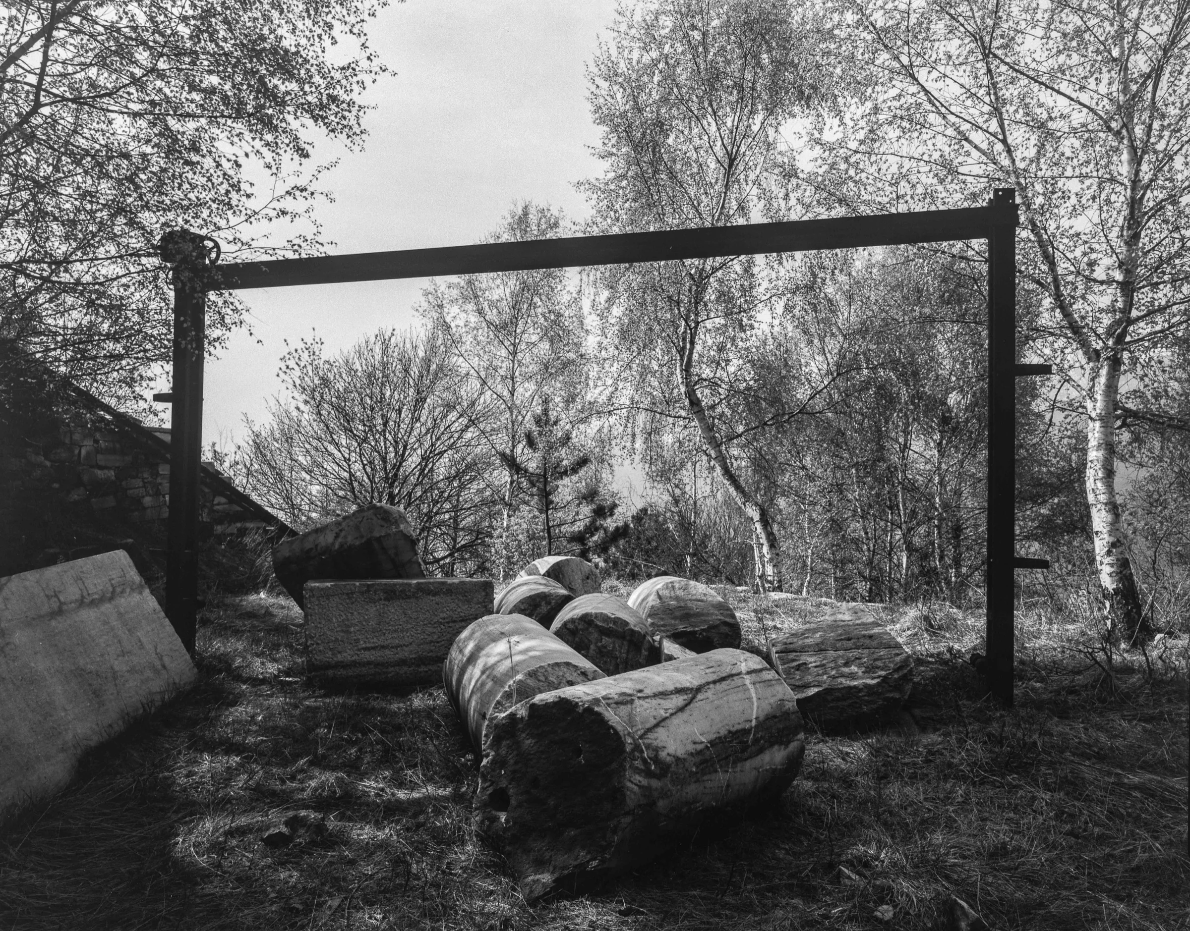 Worked cylindrical and rectangular marble blocks lie beneath a lifting frame at the Candoglia quarry in 1998