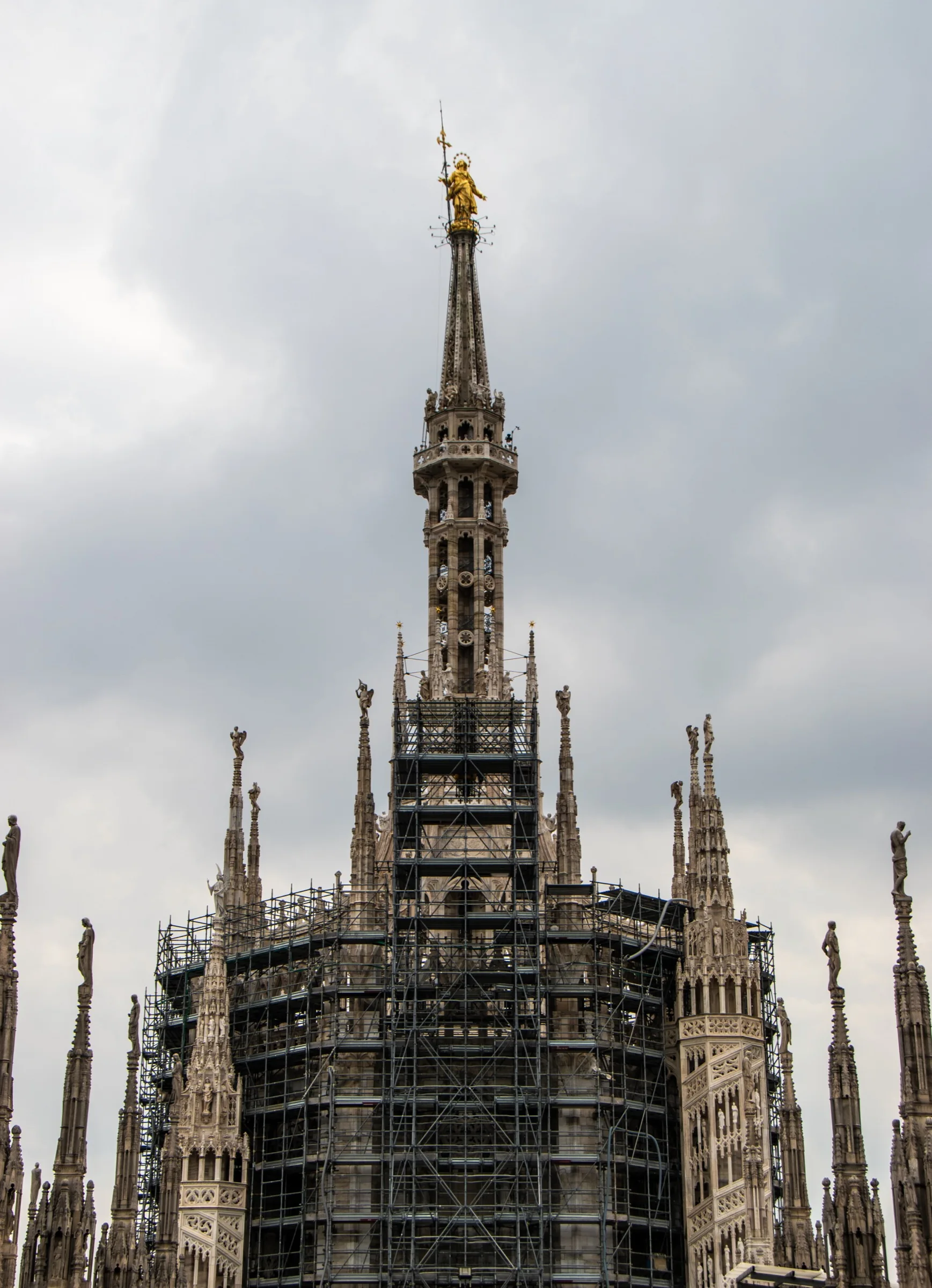 The gilded Madonnina rises above the great spire while scaffolding surrounds the tiburio below