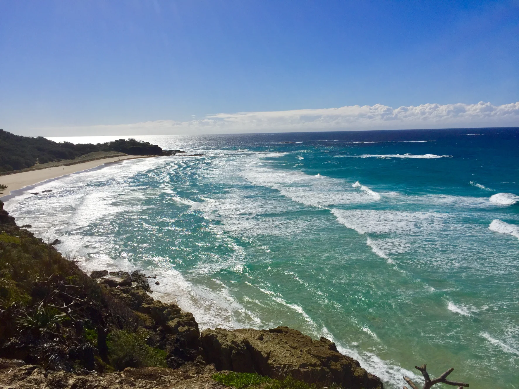 Cylinder Beach curves beneath a vegetated headland as small waves reach the shore.