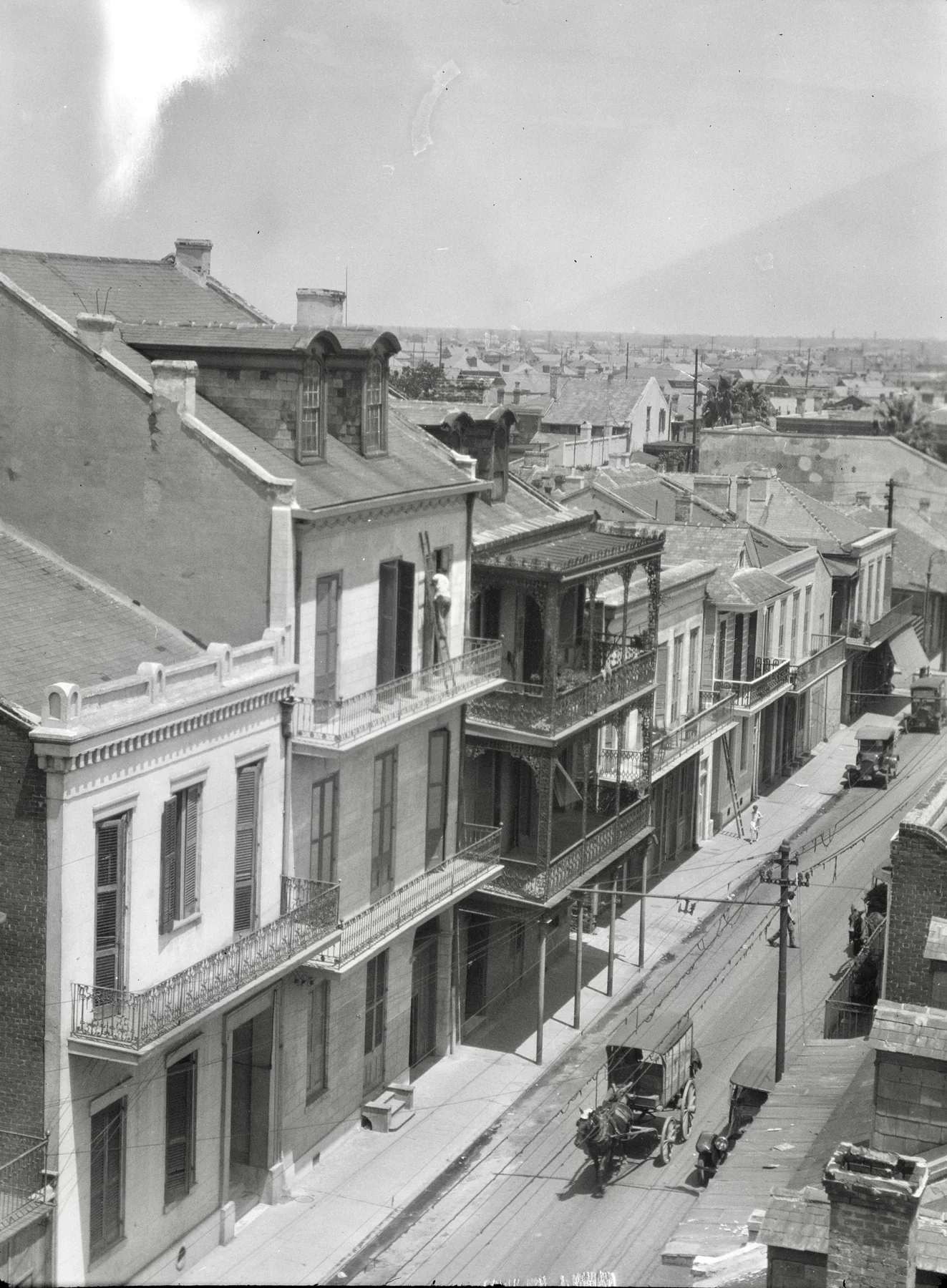 An Arnold Genthe photograph from 1923 looks over Royal Street roofs, galleries, service spaces and traffic