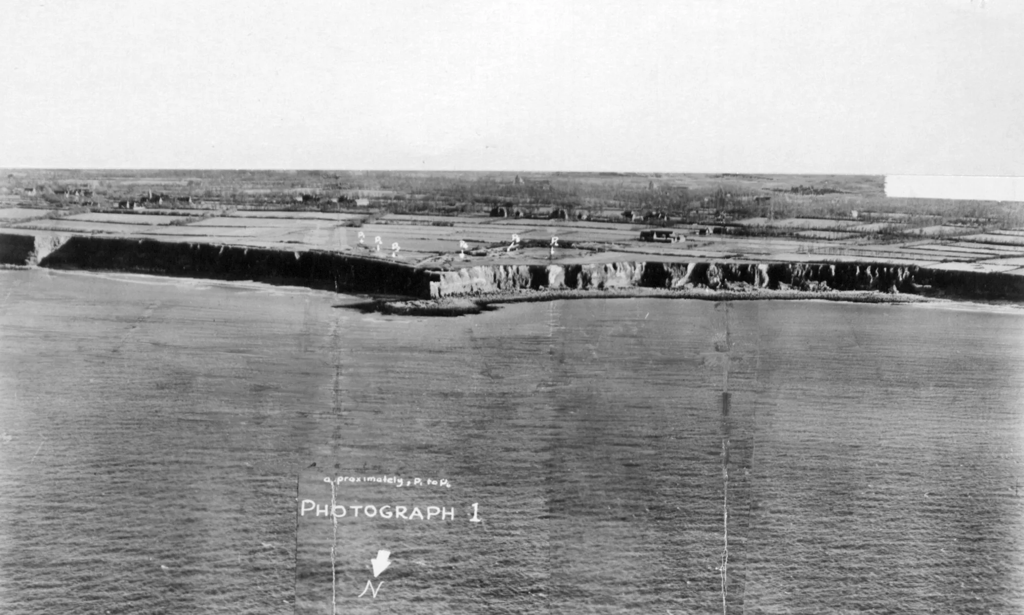 Aerial reconnaissance view of Pointe du Hoc in 1943, with open gun positions marked on the headland