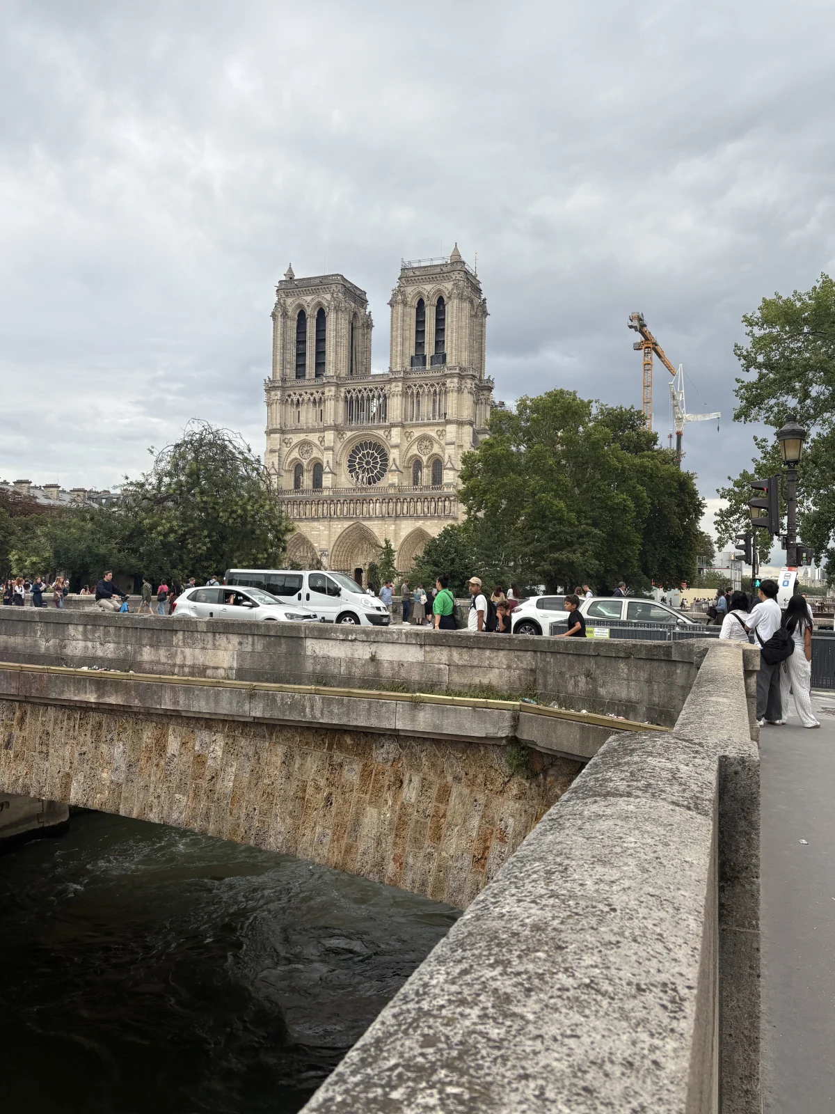 Notre-Dame seen across the Seine in July 2025 after its reopening, with the restored west front and towers beyond the river wall.