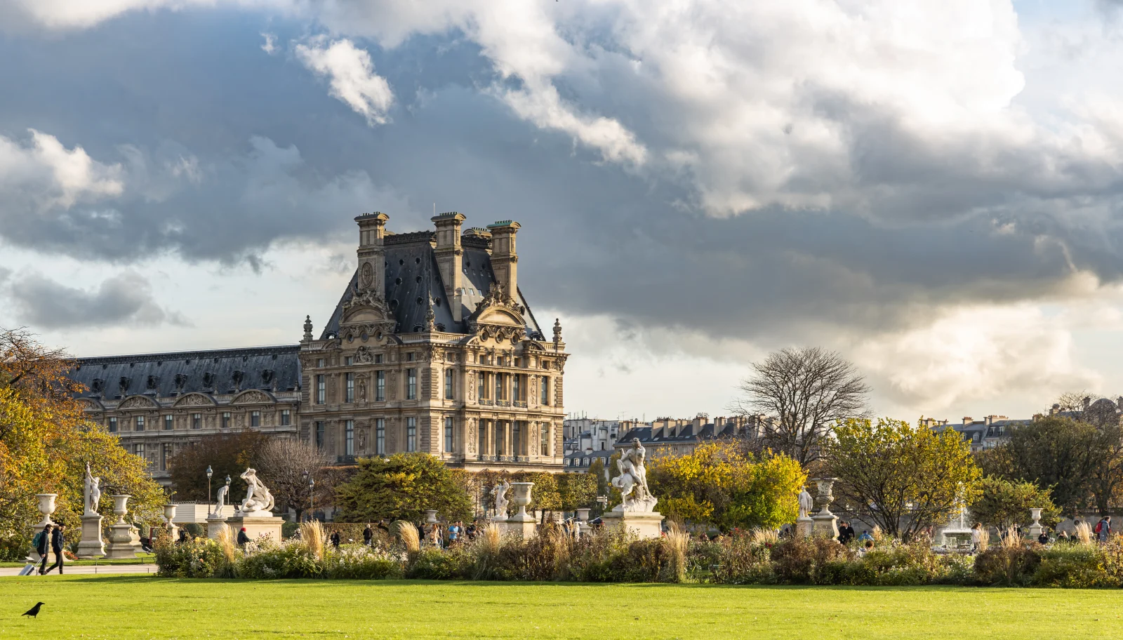 The Pavillon de Flore and Louvre edge seen from the Tuileries Garden beyond planting and sculpture.