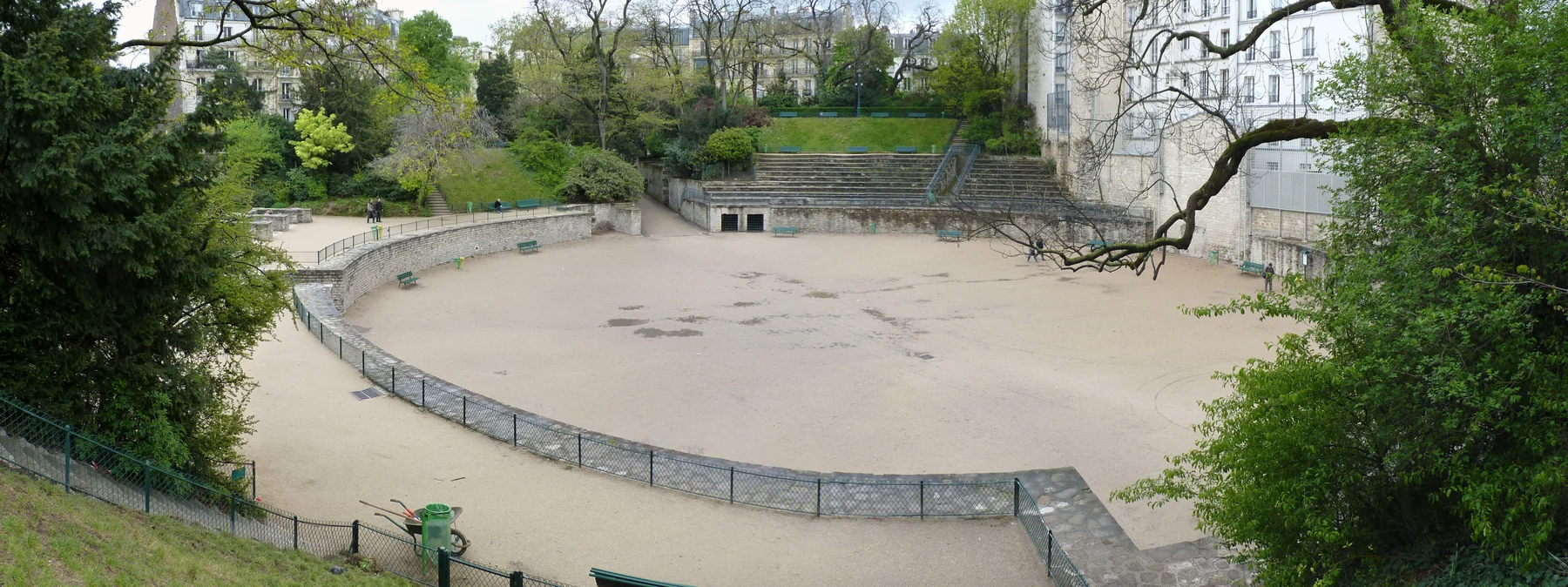 A present-day panorama shows the open arena floor, partial curved seating and the buildings that now contain the archaeological fragment.
