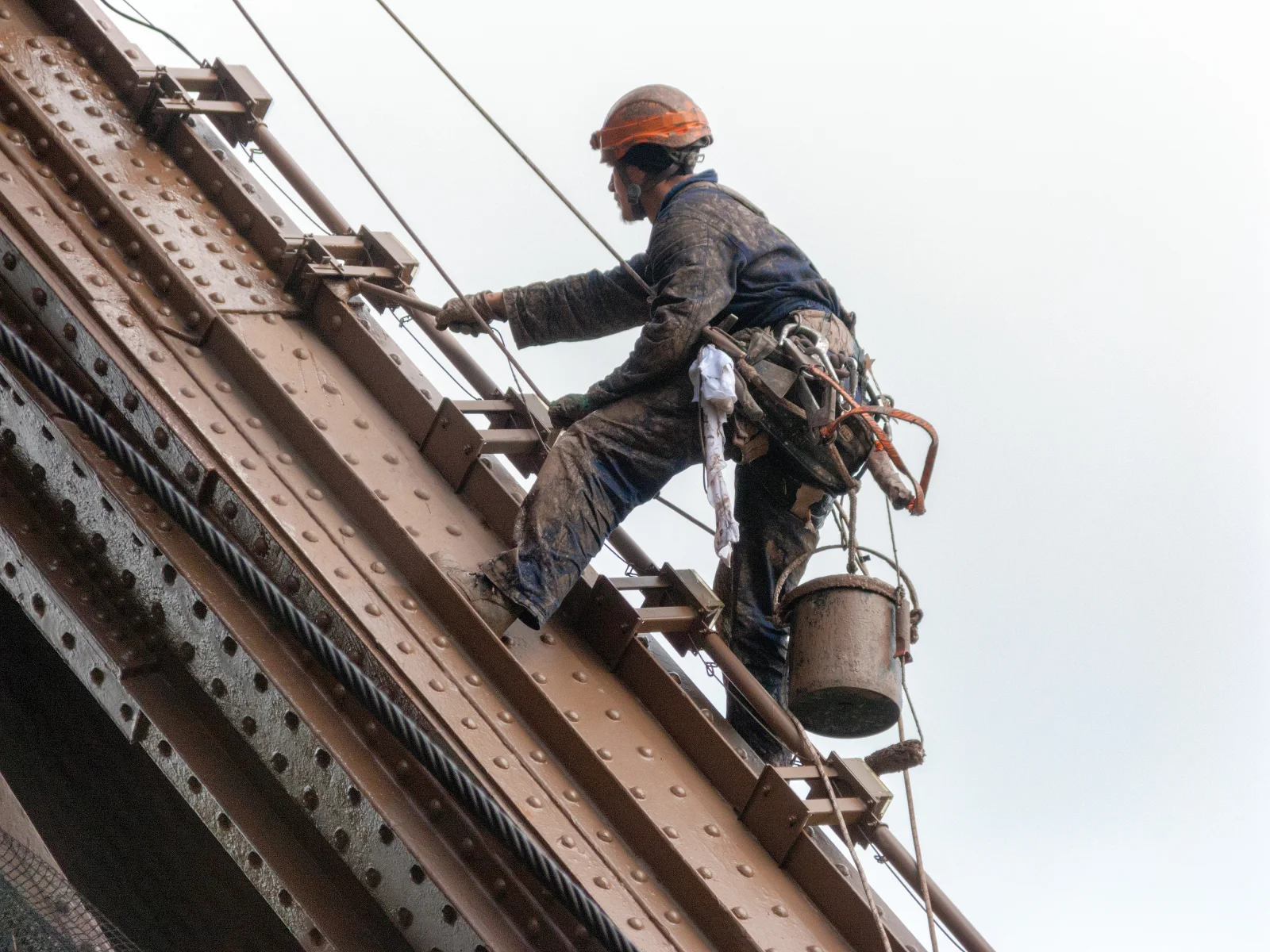 A maintenance worker positioned among the painted members of the Eiffel Tower.