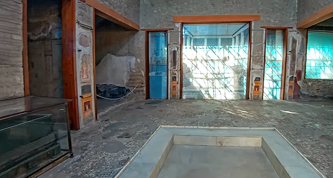 The atrium of the House of the Vettii looks through toward the colonnaded garden, with an impluvium in the foreground and painted walls around it