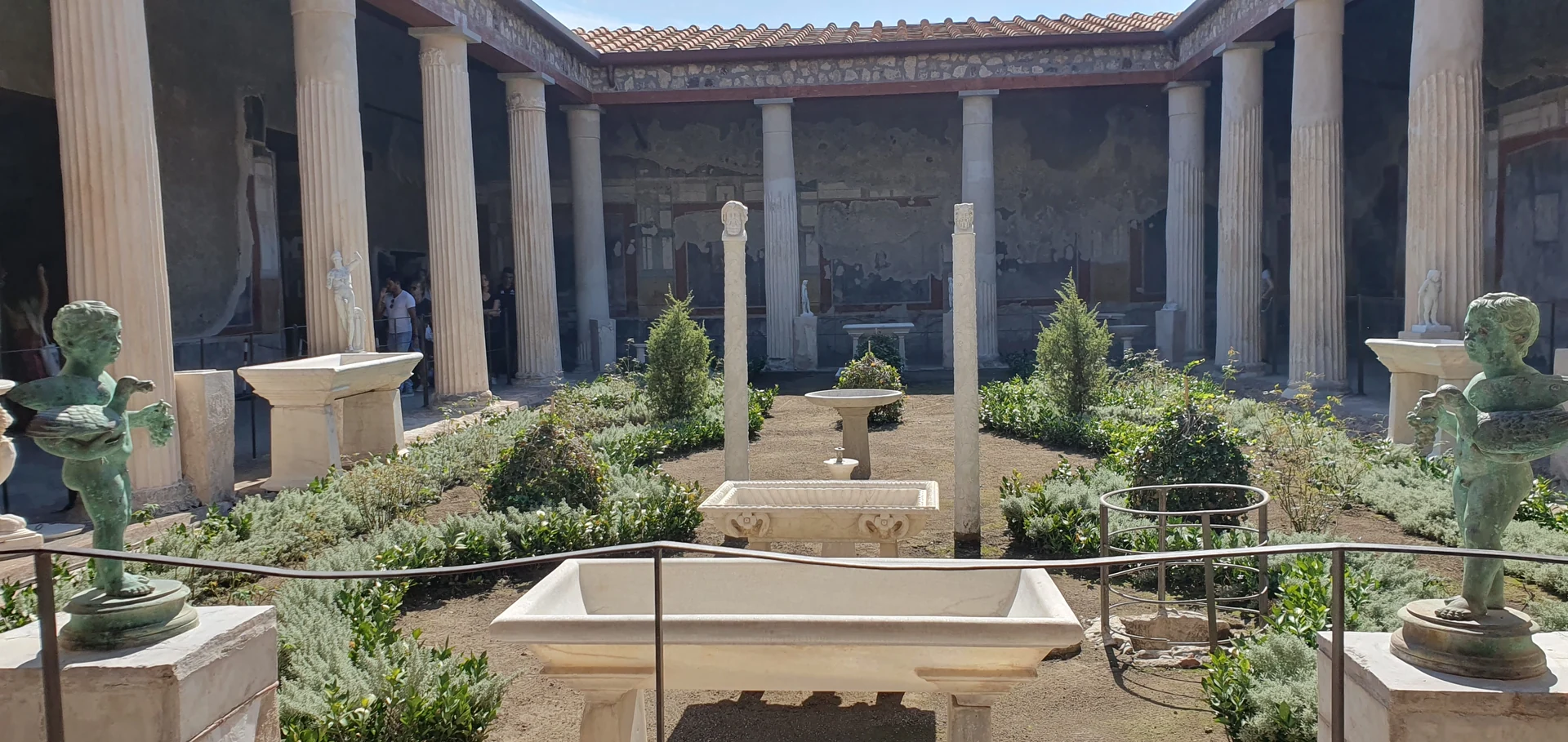 The colonnaded garden of the House of the Vettii, with planted beds, water basins and sculptural displays inside the restored visitor setting