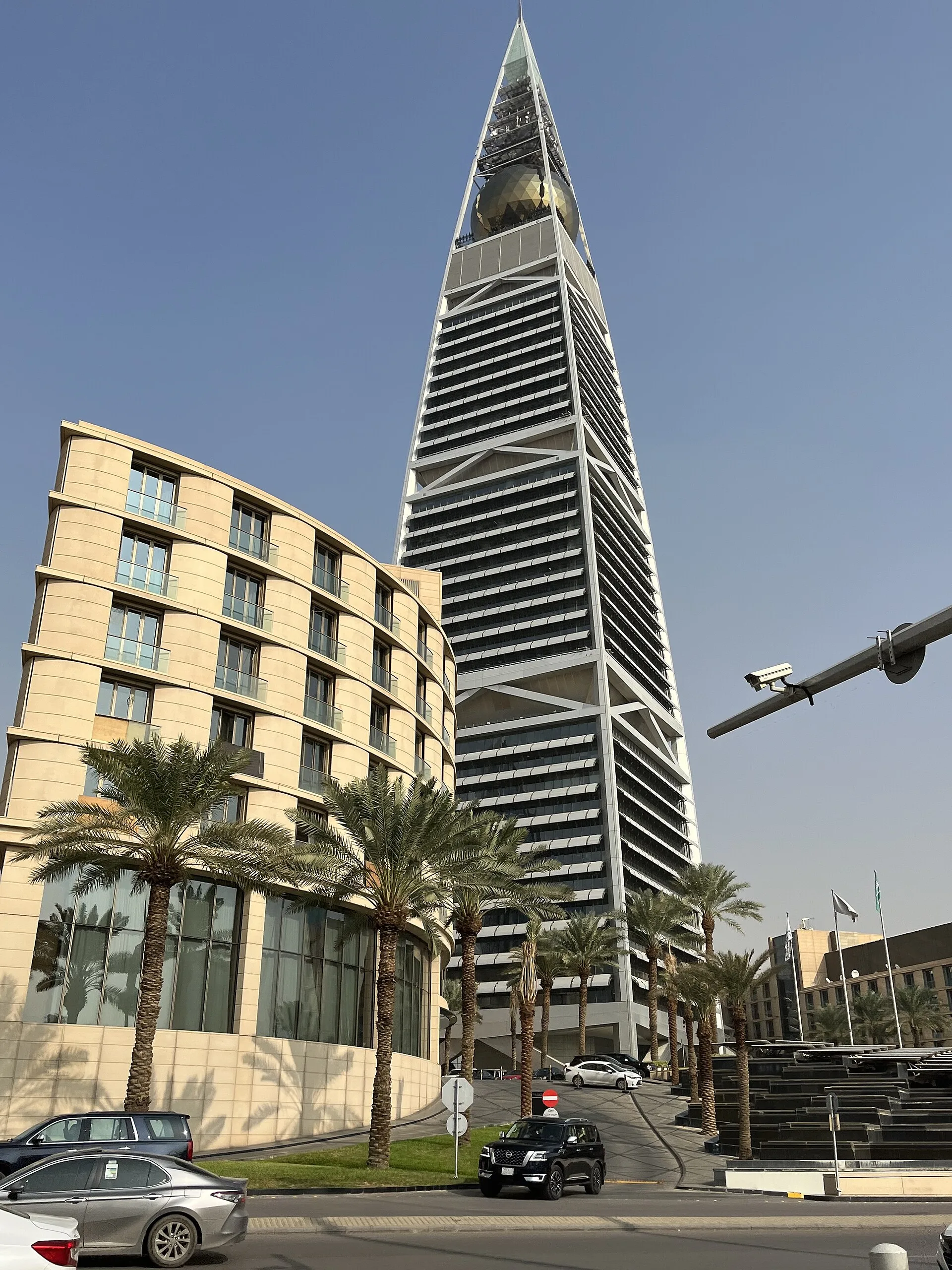 Al Faisaliah's tapered frame and golden sphere rise above palms and multilane streets.