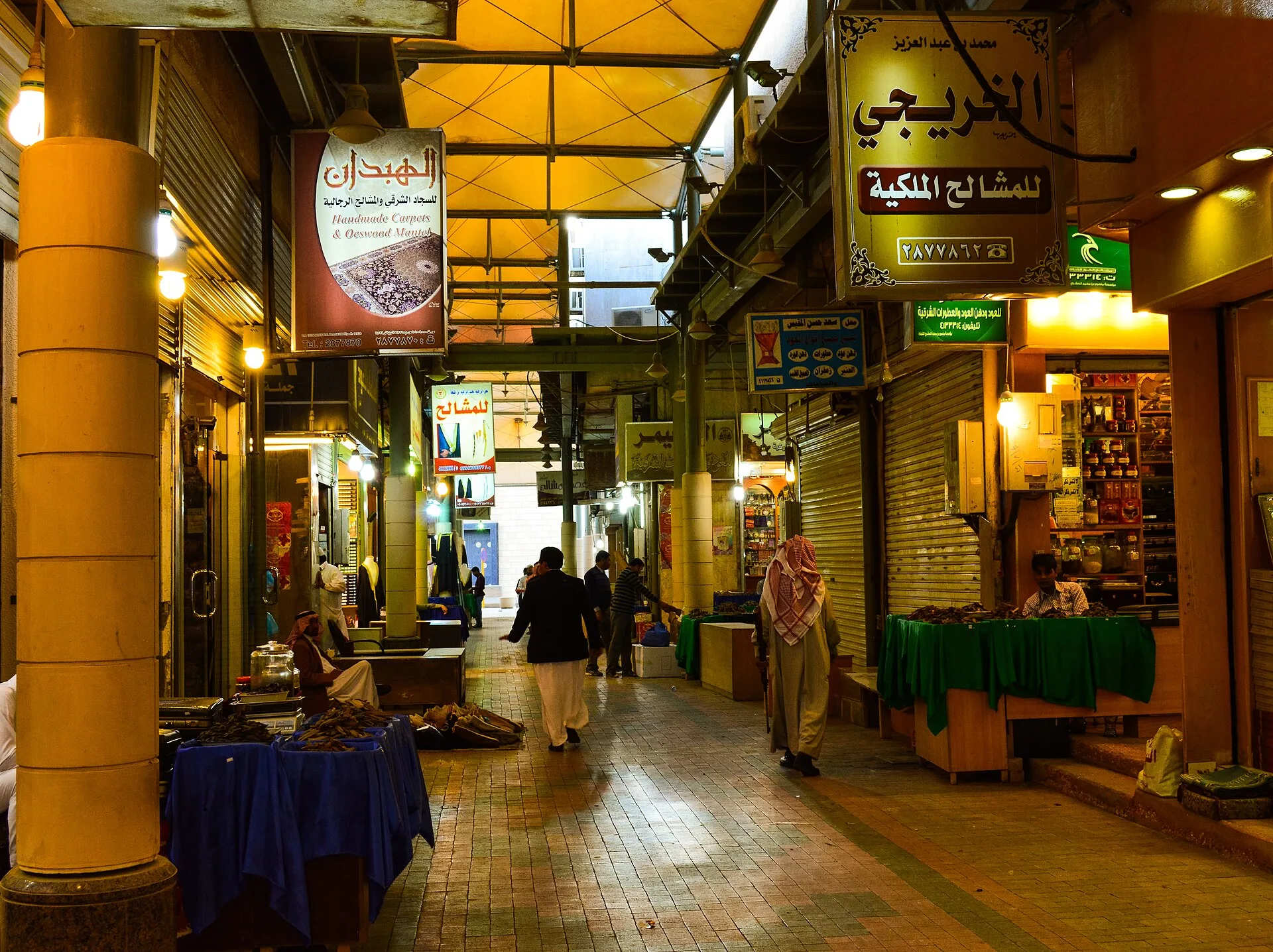 A covered downtown Riyadh market passage contains carpet, incense and clothing businesses.