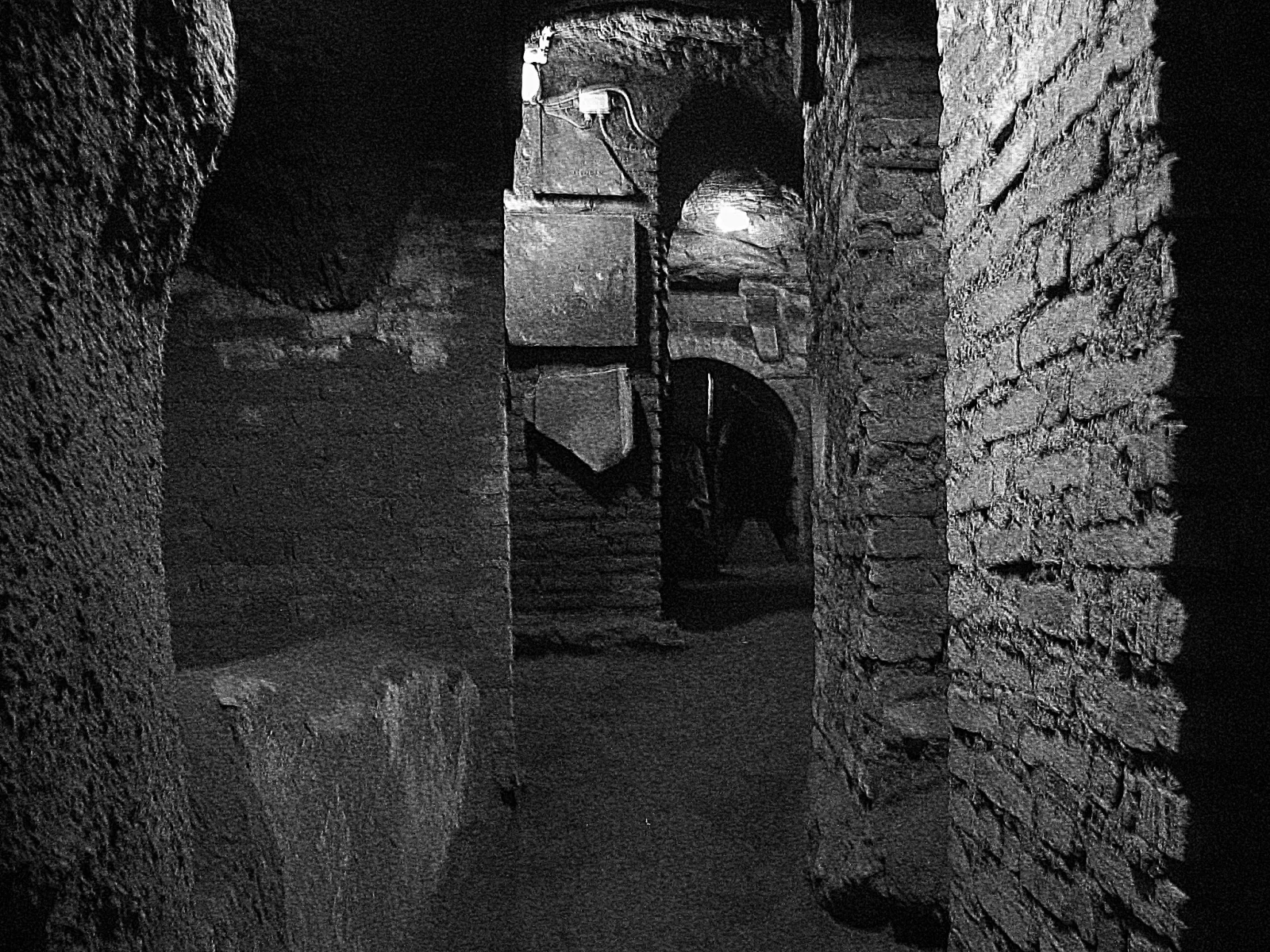 A sourced black-and-white photograph shows the narrow masonry, openings and layered interior of the San Sebastiano catacombs.