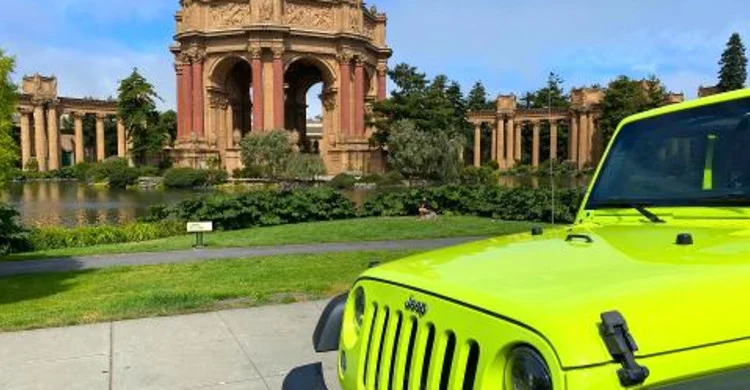 A lime-green sightseeing vehicle stands near the Palace of Fine Arts lagoon and rotunda