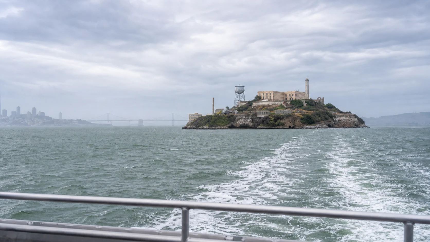 Alcatraz Island seen from the ferry route with wake, bay and headlands