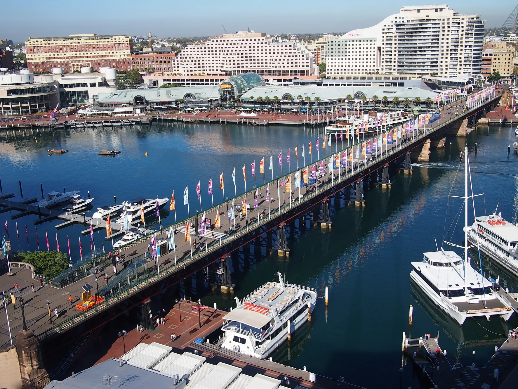 Pyrmont Bridge crosses Darling Harbour on timber and steel spans, its swing section embedded in a busy pedestrian waterfront.