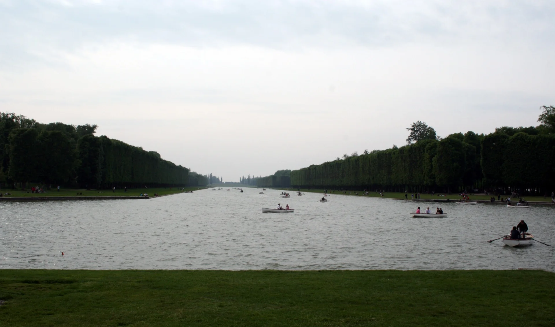 Boats on the Grand Canal at Versailles, framed by long walls of trees.