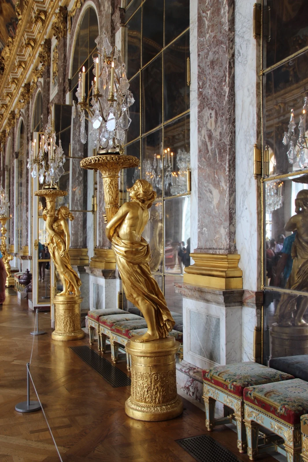 Gilded torchères and mirrored arches in the Hall of Mirrors at Versailles.