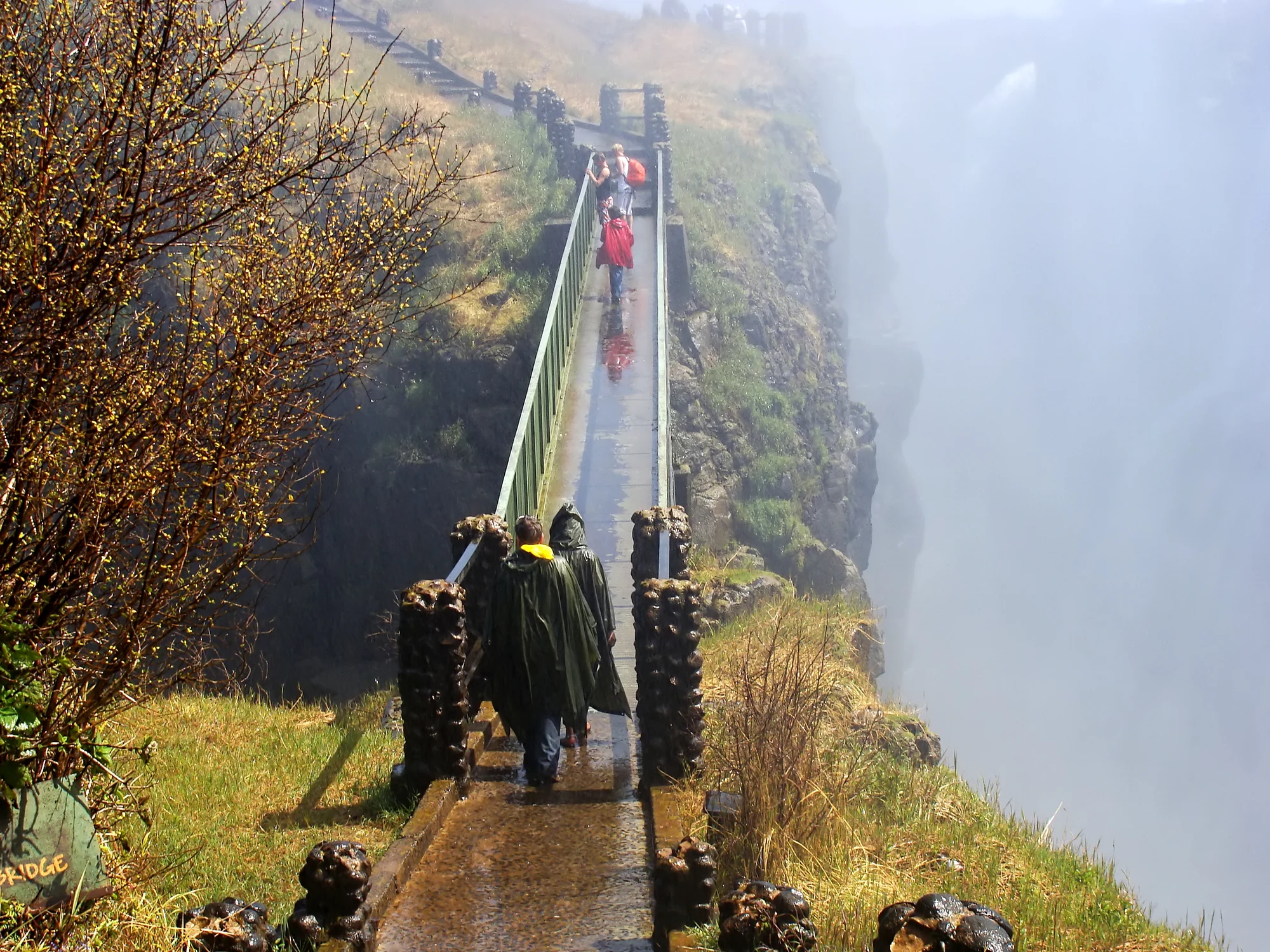 The narrow Knife-edge footbridge between basalt walls and dense spray on the Zambia-side walk