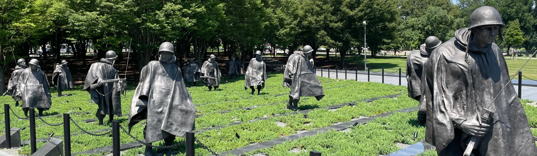 The 19 stainless-steel patrol figures of the Korean War Veterans Memorial moving through a planted field.