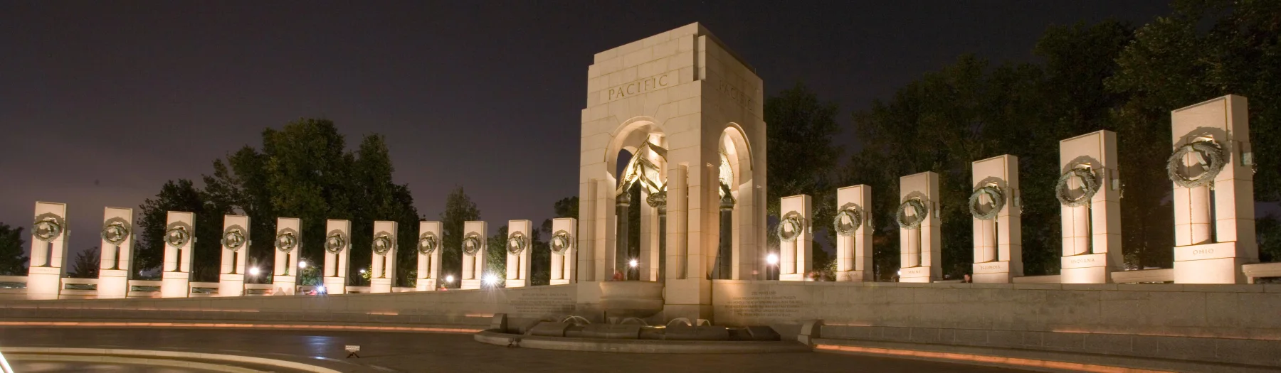 The Pacific arch and state pillars of the World War II Memorial illuminated at night.